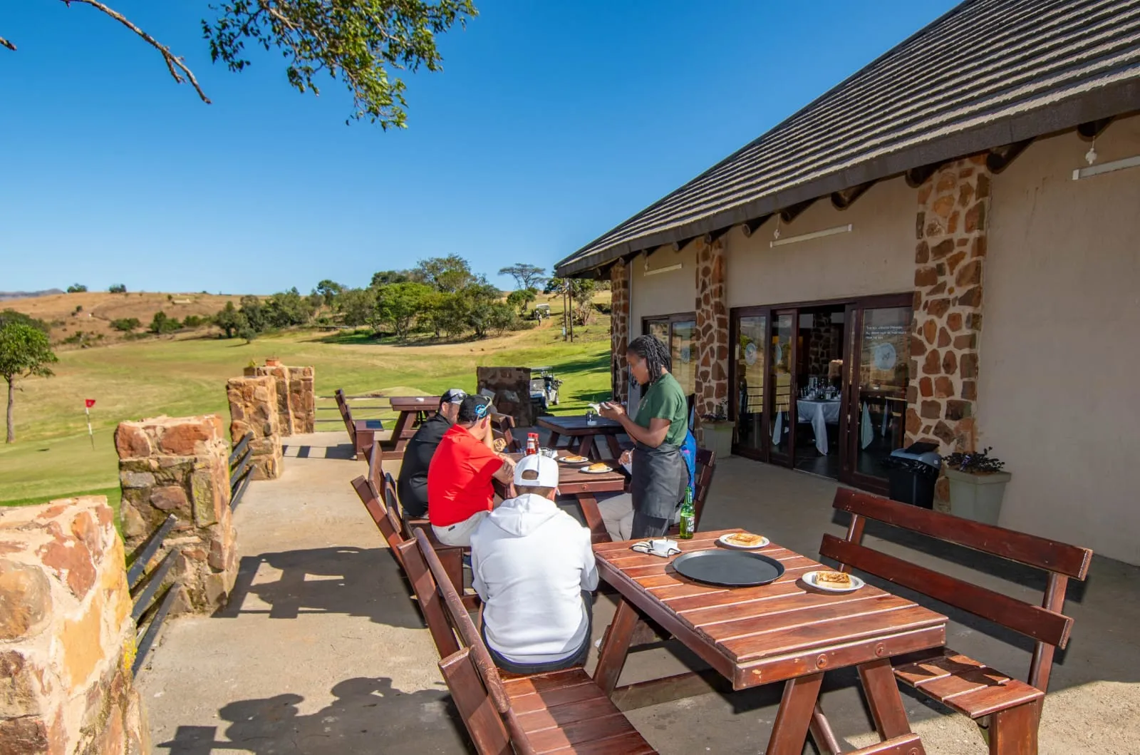 Members at lunch on the clubhouse stoep, with the course behind