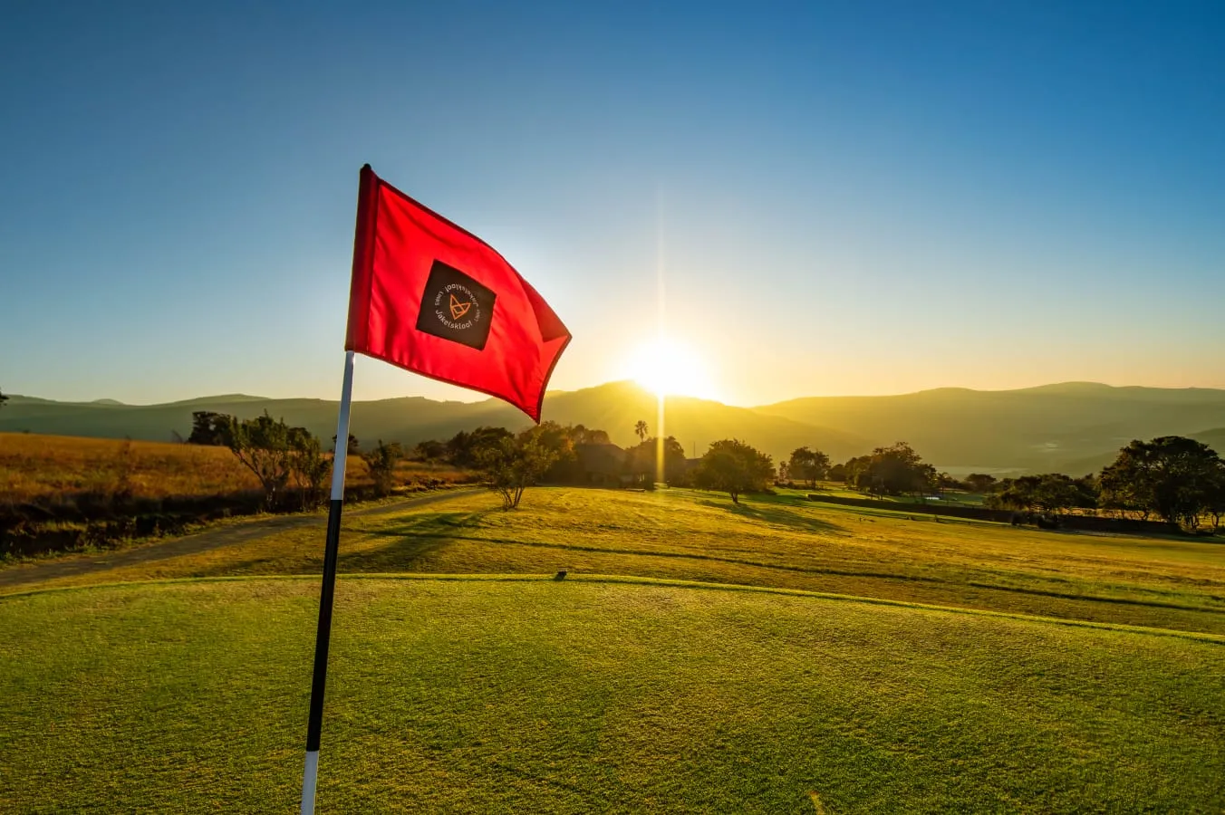 The red club flag on a green at sunrise