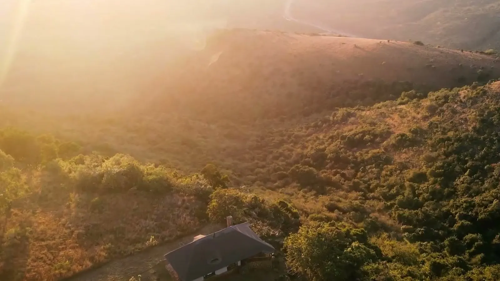 Morning sun through the haze over the valley, above a thatched chalet